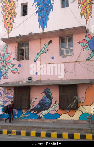 Ein Mann hinter einem Wandbild von brasilianischen Künstlern Bicicleta Sem Freio, Lodhi Kolonie, Neu Delhi, Indien Stockfoto