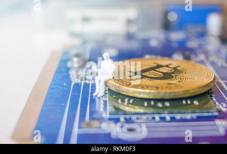 Miniatur Modell des Geschäfts Mann mit Laptop sitzen auf einem Bitcoin und Computer Teil Stockfoto