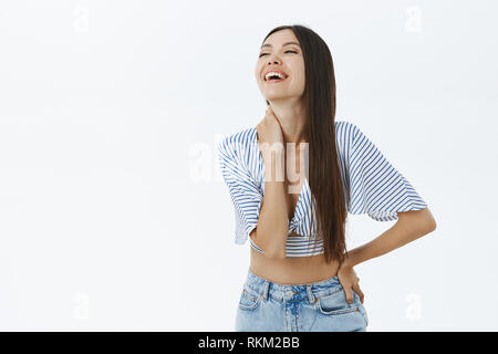 Emotionale unbeschwerte und freudige attraktive erwachsenen Frau im oberen 7/8 und Jeans in Lachen laut aus Unterhaltung und Freude berühren Hals flirty anstarrt, links Stockfoto