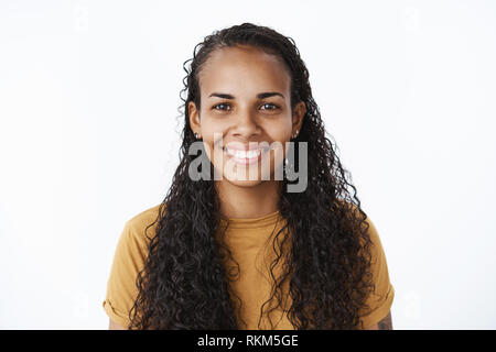 Clsose-up Shot der freudigen gut aussehende freundlich Afrikanisch-amerikanische Frau mit langen, lockigen Haaren und weissen breiten Lächeln in die Kamera blicken erfüllt und Stockfoto