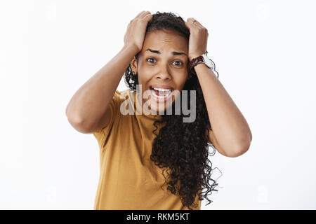 Taille-up Shot aus Angst Panik niedlichen afrikanische amerikanische Junge weibliche Schreien, Hände auf den Kopf in Verzweiflung und unter Schock stehend Ausgeflippt Stockfoto