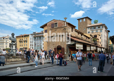 Die Leute auf der Einkaufsmeile von der Brücke Ponte Vecchio entfernt, an einem sonnigen Frühlingstag in Florenz, Italien. Die Skulptur von Benvenuto Cellinis ist auf der linken Seite. Stockfoto