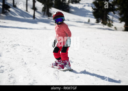 Kleinen Niedlichen 5 Jahre altes Mädchen Snowboarden ein Tricks bei Ski Resort im sonnigen Wintertag. Kaukasus Berge. Mount Hood Meadows Oregon Stockfoto