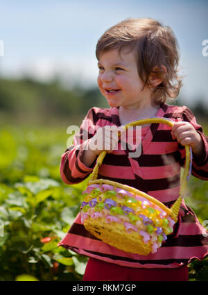 Gerne Süßes Kleinkind Mädchen Kommissionierung Erdbeeren auf dem Feld im Sommer sonnigen Tag mit Schaufel Stockfoto