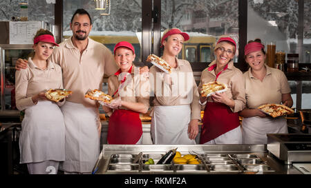 Lächelnden jungen Zeug schürzen Verkauf von Pizza in Fast Food Restaurant. Leckeres italienisches Essen Stockfoto