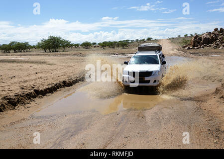 Offroad Auto 4x4 Allradantrieb. Off-road-Fahrzeug Spritzer Wasser bis zu Seiten während eines Flusses durch eine Desert Canyon, Kreuzung, Namibia Stockfoto