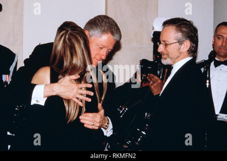 Us-Präsident Bill Clinton, Mitte, umfasst die Schauspielerin Kate Capshaw, wie ihr Ehemann Regisseur Steven Spielberg, rechts, schaut auf die Empfangsleitung während des Abendessen im Weißen Haus Februar 5, 1998 in Washington, DC. Stockfoto