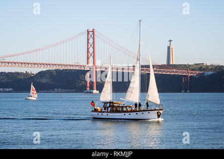 Lissabon, Portugal - 12/28/18: Segelboote mit weissen Segeln auf den Fluss Tejo, 25 April (25 de Abril) Brücke, Christus, dem König, Aufzug Turm in den hinterg Stockfoto