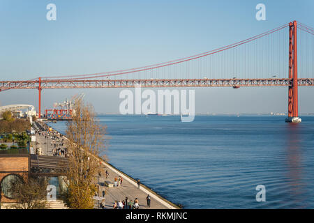 Lissabon, Portugal - 12/28/18: Fußgängerweg Riverside, den Fluss Tejo. Blick auf den 25. April rote Brücke, viele Leute, die zu Fuß Stockfoto