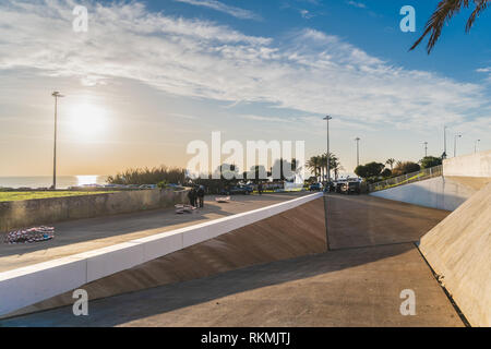 Estoril, Portugal - 12/31/18: Nova Universität Parkplatz am Strand Eingang, moderne Architektur, gerade lineare Linien, helle Sonnenuntergang auf dem Wasser widerspiegeln Stockfoto