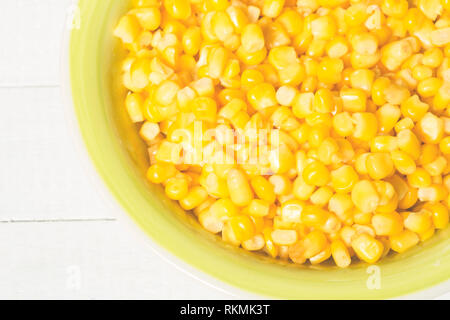 Gekochte Maiskörner in eine Schüssel geben. Stockfoto