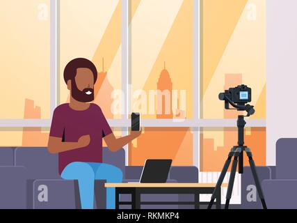Guy Technologie blogger Aufnehmen von Videos mit der Kamera afrikanischer Mann zeigt neue smartphone Funktionstests blog Konzept moderne Apartment Innenraum closeup Stock Vektor