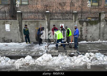 Arbeitnehmer Schneeräumen vom Fußweg, der an einem sonnigen Wintertag in Srinagar, Indien verwalteten Kaschmir. Wetter im Kaschmir-tal hat Verbesserung nach die schwersten Schneefälle gezeigt. Die wichtigsten National Highway, die das Tal mit dem Rest des Landes verbindet blieb zum sechsten Mal in Folge Tag nach einer Lawine sieben Menschen, darunter auch die drei Polizisten töten geschlossen, die zwei Feuerwehrmänner und die beiden Gefangenen. Das Wetter hat man heftige Regen- und Schneefälle von Feb 13 Prognose. Stockfoto