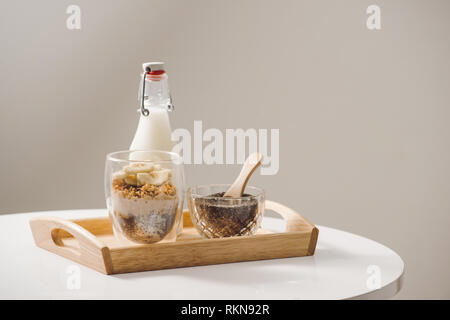 Bereit gesund Ein nahrhaftes Frühstück zu essen - Müsli mit Mandeln, Chia Samen, Banane und Kiwi Früchte und Beeren und ein Glas mit Milch in der Nähe Stockfoto