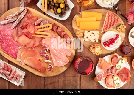 Charcuterie Verkostung. Ein Foto von vielen verschiedenen Wurst und Schinken, Aufschnitt, und eine Käseplatte, geschossen von oben auf eine rustikale Hintergrund mit Wein Stockfoto