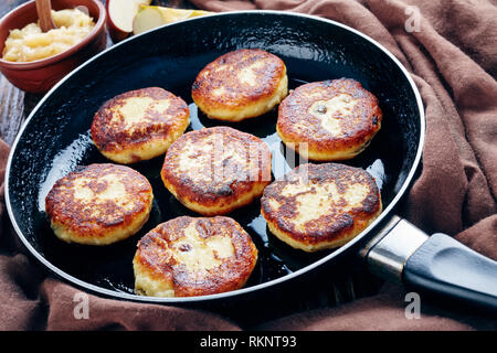 Lecker Quark Kartoffelpuffer mit Rosinen - quarkkeulchen in einer Pfanne auf einem alten Holztisch mit braunen Tuch und Apple Mousse in eine Schüssel geben, Stockfoto