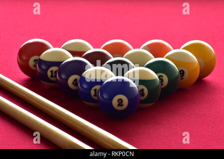 Nummerierte Kugeln mit zwei pool Cues auf rotem Filz Tisch. Stockfoto