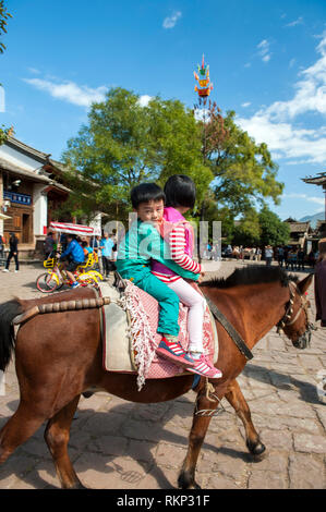 Ponyreiten rund um den Marktplatz in Sideng Shaxi, einem ehemaligen Handelsstadt für Wohnwagen auf den Tee Reiten in Jianchuan County, Yunnan provi Stockfoto