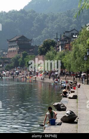 Einheimische Waschmaschine Bettwäsche und Kleidung in den Tou Jiang River bei Fenghuang. Was bedeutet "Phoenix" auf Chinesisch, Fenghuang wurde nach dem mythischen Vogel, der imm benannt Stockfoto