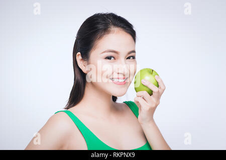 Attraktive lächelnde junge asiatische Frau Grün essen Apple auf weißem Hintergrund. Stockfoto