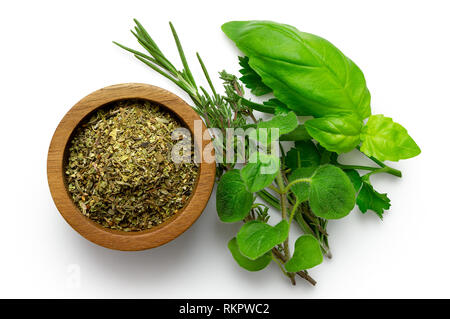 Getrocknete gehackte Provence Kräuter in einem dunklen Holz Schüssel neben frischen bouquet garni auf weiß von oben isoliert. Stockfoto