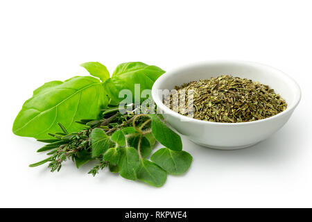 Gehackte getrocknete Kräuter der Provence in einem weißen Keramik Schüssel neben frischen bouquet garni isoliert auf Weiss. Stockfoto