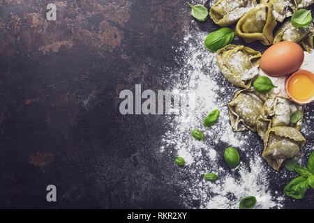 Frisches Basilikum Tortellini mit Zutaten auf einem dunklen Untergrund, Ansicht von oben Stockfoto