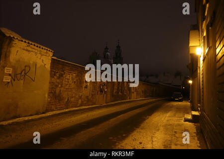 Geheimnisvolle Blick auf die Altstadt Straße im Winter in der Nacht. Vilnius, Litauen. Die Kirche St. Katharina auf dem Hintergrund. Stockfoto