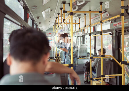 HO CHI MINH CITY, VIETNAM - 22 Juli, 2017: hübscher junger Mann in eine blaue Jeansjacke mit Smartphones im Bus Stockfoto