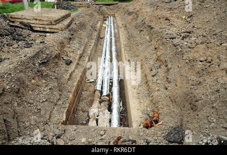 Installation und Isolation hot water Pipeline für Energieeinsparung und Energieeffizienz. Reparatur, Isolierung und Erneuerung der Kanalisation auf der Straße Stockfoto