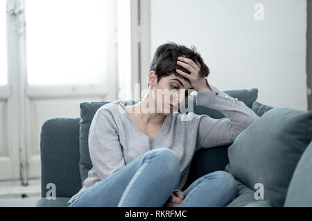Porträt der Schönen verzweifelt und deprimiert junge Frau auf Sofa traurig, hoffnungslos und in den Schmerz, die unter Depressionen leiden, in den Menschen, die psychische Gesundheit Stockfoto