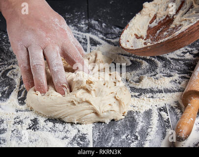 Die Hände des Menschen Weizenmehl Teig kneten Weiß auf Schwarz Holz- Hintergrund Stockfoto