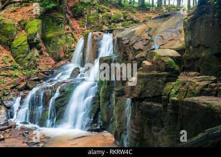 Wasserfall im Wald. schöner Frühling Landschaft. Wasser kommt aus der felsigen Klippen. wild Rapid stream. gefallene Laub unter den Bäumen und bemoosten Felsen. bri Stockfoto