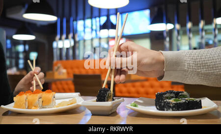 Glückliches Paar essen Sushi Rollen in Japan Restaurant, Sushi Bar. Japanisches Essen, Diät, Diät. Stockfoto