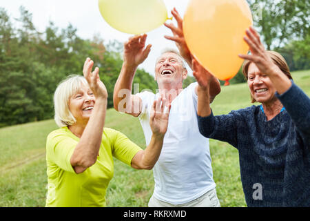 Happy Senioren spielen mit Ballons zu einem Sommerfest im Park Stockfoto