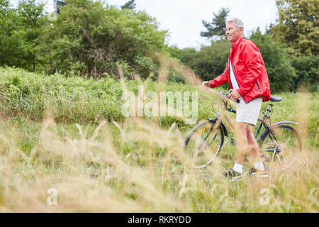 Sportliche älterer Mann Züge seiner Eignung mit dem Fahrrad auf dem Fahrrad Stockfoto