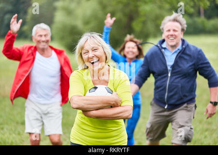 Gerne ältere Frau mit Kugel und jubeln Freunde nach einem Fußballspiel Stockfoto