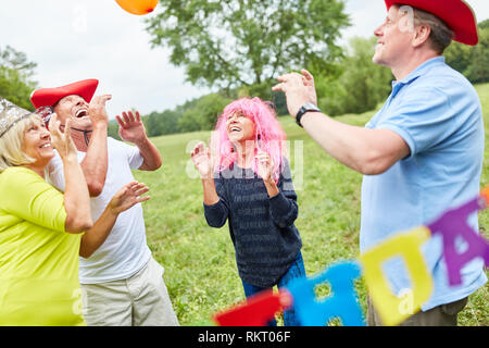 Feiern Gruppe von Senioren und in bunten Kostümen auf einer Geburtstagsparty spielen Stockfoto