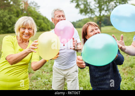 Happy Senioren als Freunde mit Ballons feiern Geburtstag zusammen Stockfoto