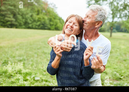 Senioren als glückliches Paar im Park buchstabiere das Wort Liebe Stockfoto