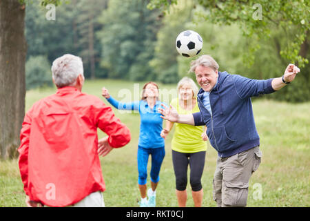 Älterer Mann spielt Header in ein Fußball-Spiel gemeinsam mit Freunden Stockfoto