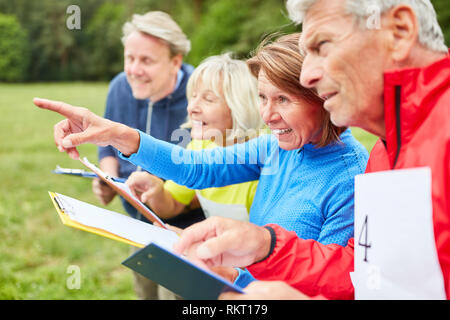 Senioren Mannschaft in einer Schnitzeljagd löst Aufgaben in der Natur zusammen Stockfoto