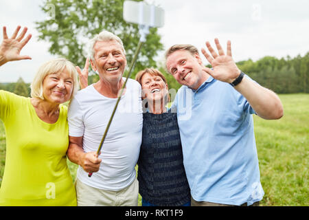 Senioren haben Spaß dabei selfie Foto mit dem selfie Stick und winken Stockfoto