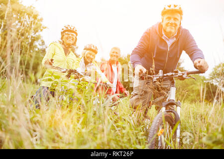 Aktive Gruppe von Seniorinnen und Senioren mit dem Fahrrad gemeinsam Radfahren im Sommer Stockfoto