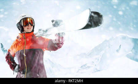 Skifahrerin stehend mit Himmel in einer Hand auf die schöne Berglandschaft im Hintergrund. Winter, Ski, Schnee, Urlaub, Sport, Freizeit, Lifestyle Konzept Stockfoto