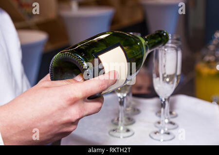 Der Kellner gießt Sekt in die Gläser aus einer Flasche in ein Restaurant. Gastronomie, Bankett Stockfoto