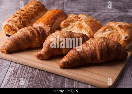 Reihe von frischen leckeren Gebäck auf Schneidebrett. Goldene Kruste. Stockfoto