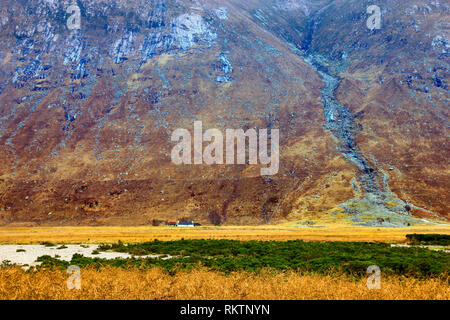 Ein Blick auf eine abgelegene Farm von einem hoch aufragenden Berg in den schottischen Highlands in den Schatten gestellt. Stockfoto