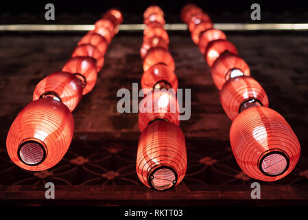 Gruppe von roten Lampions an der Wand aufhängen, nachts für das Chinesische Neue Jahr beleuchtet Stockfoto