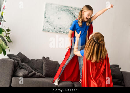 Kind und Mutter in roten Mänteln zu Hause spielen Stockfoto